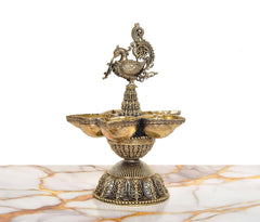 Five-diya brass oil lamp with peacock topper, round carved base