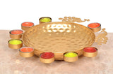 Gold decorative urli with peacock filigree handles and surrounding tea light cups