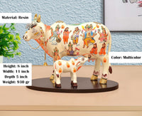 Resin Kamdhenu cow statue with calf, multicolor patterned bodies on dark round base