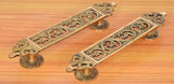 Ornate brass filigree flower door pulls on wooden door panel, two-piece pair