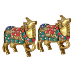Brass cow statues pair, side view with detailed legs and colorful saddle