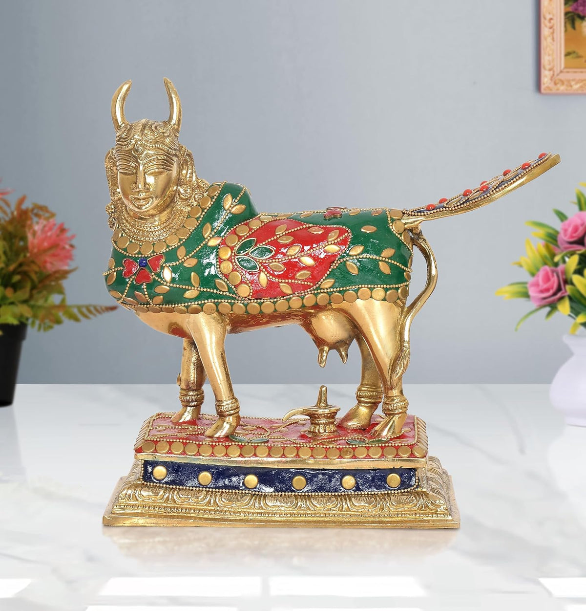 Brass Kamdhenu cow showpiece, green-red decorated body, raised tail, ornate face