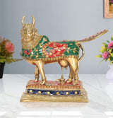 Brass Kamdhenu cow showpiece, green-red decorated body, raised tail, ornate face