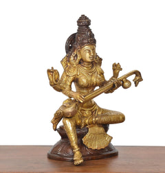 Seated brass Saraswati goddess idol with veena, raised hands and ornate back details