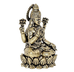 Lakshmi brass idol, side view, crowned figure with four raised hands, seated on lotus base