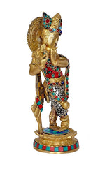 Side view brass Krishna statue with colorful inlay and ornate halo, on base