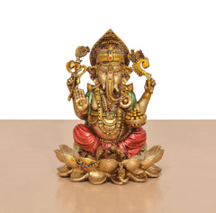 Close view of Ganesh resin figurine seated on lotus, red draped cloth and gold