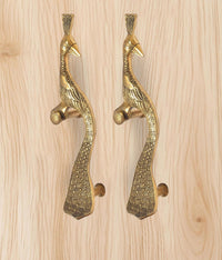 Two brass peacock door handles mounted on light wood, golden tone