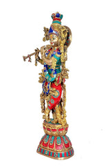 Brass Krishna murti side view, jeweled crown and halo, blue-red clothing, flute in hand