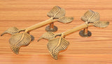 Twin-leaf brass door handle pair with leaf finials and round rosette base
