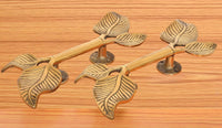 Twin-leaf brass door handle pair with leaf finials and round rosette base