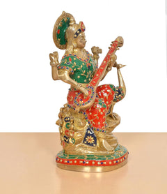Saraswati idol profile holding veena, green headpiece and red skirt with ornate patterns