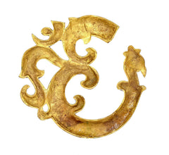 Gold-tone OM wall sculpture close-up with ornate curled cutout details