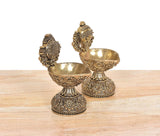 Two brass diya shankh oil lamp stands with carved feet and embossed bowl patterns