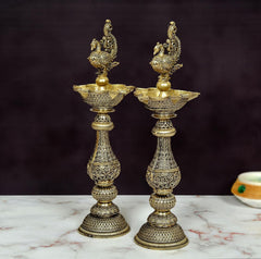 Peacock-shaped oil lamps set of 2 with tiered carved bases and top finials.