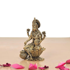 Brass Lakshmi idol angled view, holding pot and staff, decorative headdress