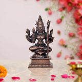 Copper-tone seated deity sculpture with four arms and trident, on engraved base