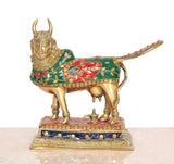 Brass pooja cow figure, front view with decorative saddle blanket and golden horns