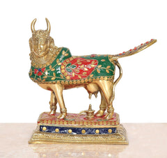 Brass pooja cow figure, front view with decorative saddle blanket and golden horns