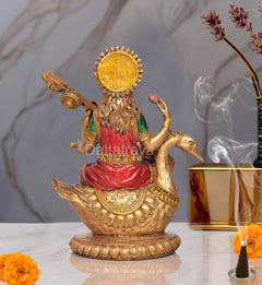 Rear view of Saraswati idol resin statue on swan, veena; gold back halo with red outfit