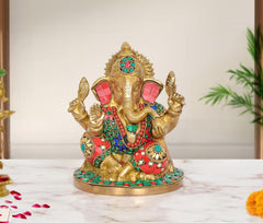 Brass Ganesha idol with colorful studded crown, red-and-green ornaments, raised arms, 7.5 in