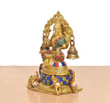 Brass Lakshmi statue side view with multicolored beadwork, crown, and hanging bells