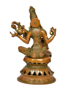 Back view of brass Saraswati statue with veena and ornate headdress, seated on base
