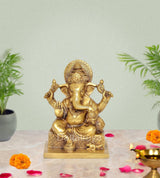 Brass Ganesha sculpture, seated with four arms and ornate crown, 7 inch height