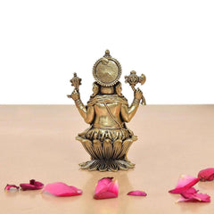 Brass Lord Ganesha idol, back view, circular halo and patterned garments.