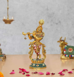 Metal Lord Krishna sculpture playing flute, gold finish with red and blue base details