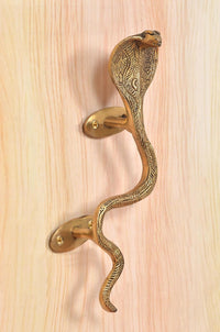 Brass snake door handle with coiled tail design and golden mounting plates