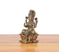 Side view of Lakshmi deity murti seated on lotus with jeweled crown and arms