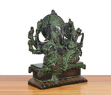 Brass Ganesha idol angled view, multiple hands and figures, green-bronze patina on base