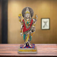 Dhanvantari brass statue with red and teal robe, gold details, raised hands on patterned base.
