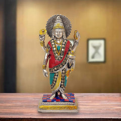 Dhanvantari brass statue with red and teal robe, gold details, raised hands on patterned base.