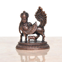 Copper winged Kamadhenu cow statue, raised ornament details, on circular pedestal base.