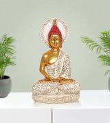 Gold Buddha figurine with red jeweled headpiece and patterned white robe, seated