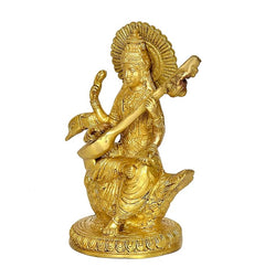 Golden brass Saraswati idol on swan, angled view with raised hands and veena