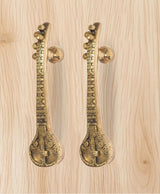Golden brass sitar-shaped door handle pair with spherical knobs and engraved base