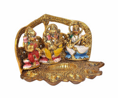Close angle painted metal diya with Ganesh, Lakshmi and Saraswati on gold base
