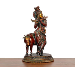 Brass standing Krishna with cow, side view showing crown, jewelry, and patterned garment
