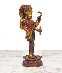 Maa Saraswati brass sculpture, angled view with raised weapon and staff