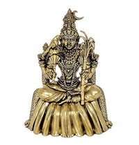 Close-up brass goddess idol, gold tone seated pose with layered jewelry and staff