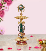 Brass chakra oil lamp diya with painted green-red deity and three bowl tiers on base