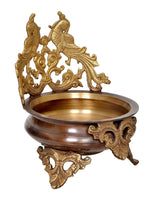 Brass peacock urli bowl with dark wooden base, brass legs, and side carvings