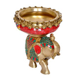 Brass elephant idol with red urli bowl and curved trunk, teal and red accents