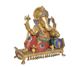 Brass Ganesha idol in profile with multi-color ornaments and hanging bells along the base