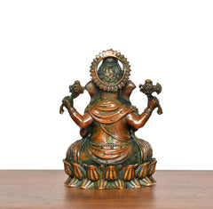 Back view of brass Lord Ganesha idol, seated with ornate halo and four arms