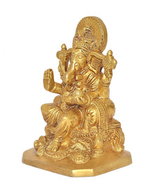 Golden Ganesha deity statue with lifted hand ornaments, seated on round pedestal
