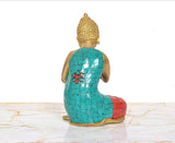 Brass Buddha idol from behind, teal back and blue robe with red patterned bottom